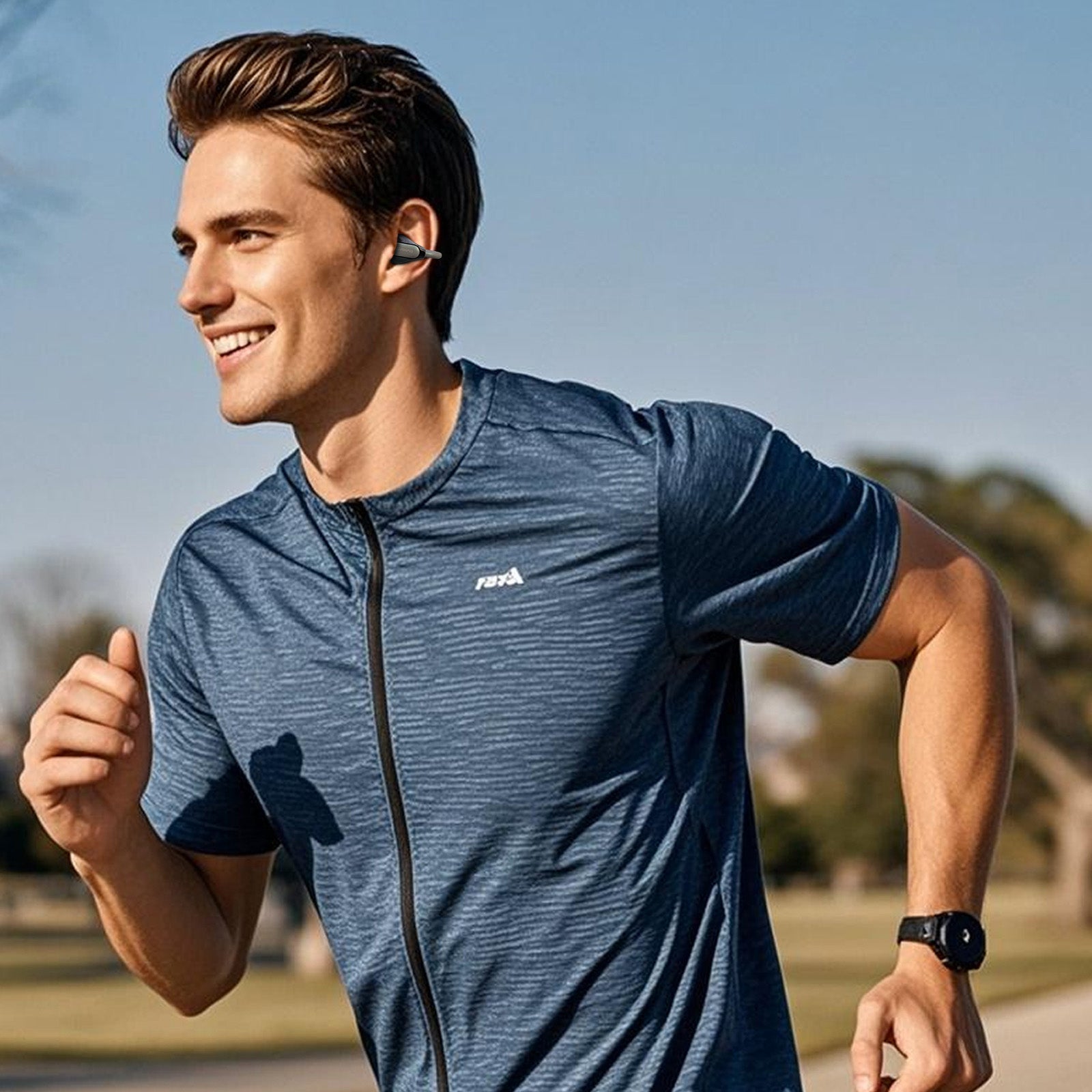 A young man jogs in a park, wearing a blue zip-up shirt and fitness tracker, earbuds in, smiling. It's a sunny day.